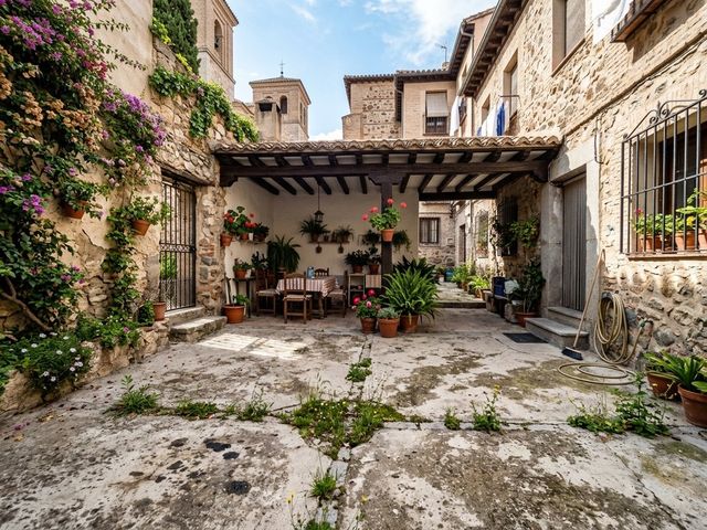 Patio de casa de piedra con suelo de cemento agrietado y hierbas antes de la obra en Torrijos