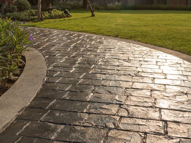 Camino curvo de jardín en hormigón impreso molde adoquín tono pizarra con bordillo redondeado