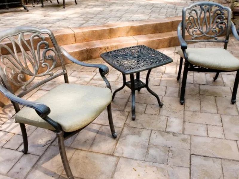 Patio con mesa y sillas de exterior sobre hormigón impreso molde losa en tono arena
