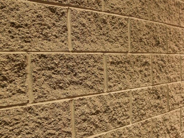 Muro de parcela revestido en vertical con relieve de bloques de piedra