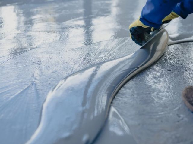 Operario extendiendo resina sobre un pavimento para igualar la superficie