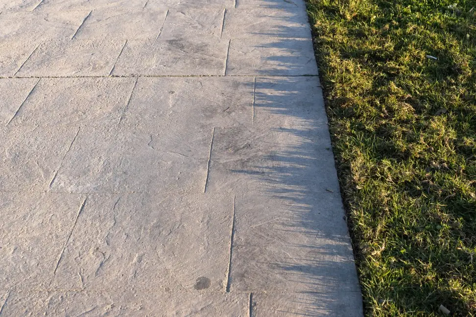 Camino perimetral de hormigón impreso molde losa de pizarra tono gris junto al césped — Seseña, Toledo